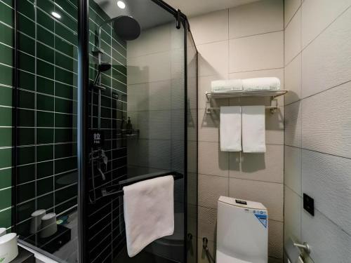 a bathroom with a shower and a toilet with green tiles at GreenTree Inn Express Hebei Tangshan Guyan District Xinguang Road in Tangshan