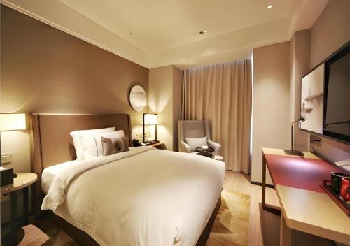 a hotel room with a bed and a television at E-Cheng Hotel Liuzhou Sanjiang Fengyu Bridge in Sanjiang