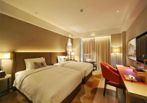 a hotel room with two beds and a desk at E-Cheng Hotel Liuzhou Sanjiang Fengyu Bridge in Sanjiang