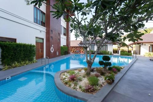 a swimming pool with a tree next to a building at The La-Ngu Boutique in Satun