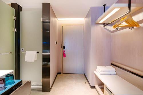 a bathroom with a sink and a white door at Echarm Hotel Suzhou Shengze Oriental Extile City in Suzhou