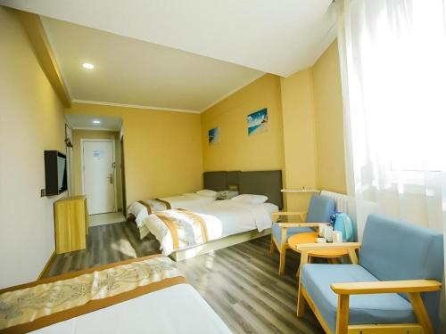 a hotel room with two beds and chairs and a tv at GreenTree Alliance Hotel Qinghuangdao Wanda Plaza in Qinhuangdao