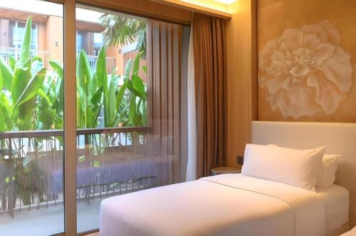a bedroom with a bed and a large window at Riverton Hotel in Samut Songkhram
