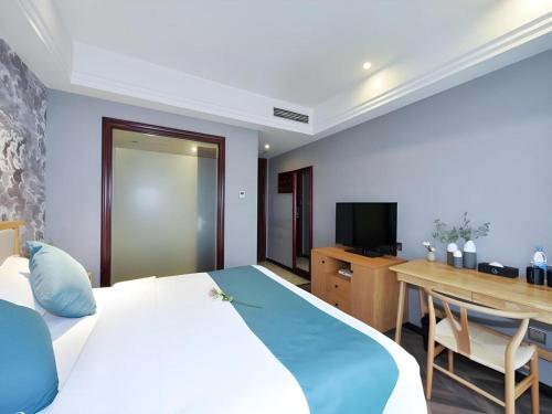 a bedroom with a bed and a desk and a television at VX Hotel Chengdu Shuangliu Airport Sainawei in Chengdu