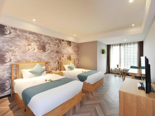 a hotel room with two beds and a television at VX Hotel Chengdu Shuangliu Airport Sainawei in Chengdu