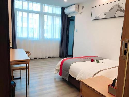 a hotel room with a bed and a window at Jun Hotel Guangdong Zhanjiang Xiashan South Railway Station in Zhanjiang