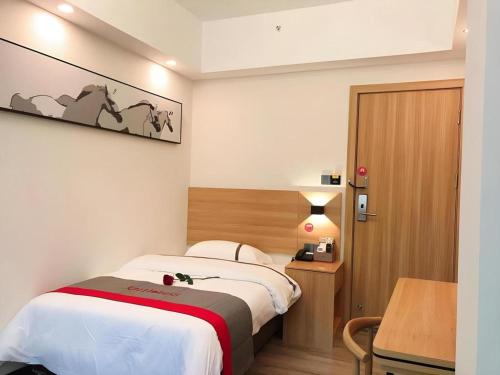 a bedroom with a bed and a desk and a table at Jun Hotel Guangdong Zhanjiang Xiashan South Railway Station in Zhanjiang
