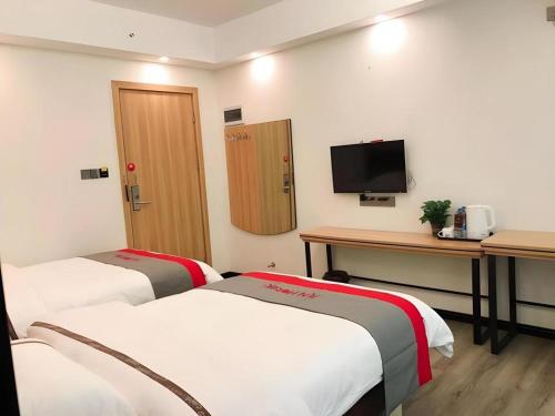 a room with two beds and a desk and a tv at Jun Hotel Guangdong Zhanjiang Xiashan South Railway Station in Zhanjiang