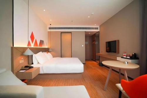 a hotel room with a bed and a desk and a tv at Borrman Hotel Zhonghsan Guzheng Huayi Plaza Light Rail Station in Zhongshan