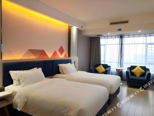 a hotel room with two beds and a chair at Borrman Hotel Liuzhou High-Speed Railway Station in Liuzhou