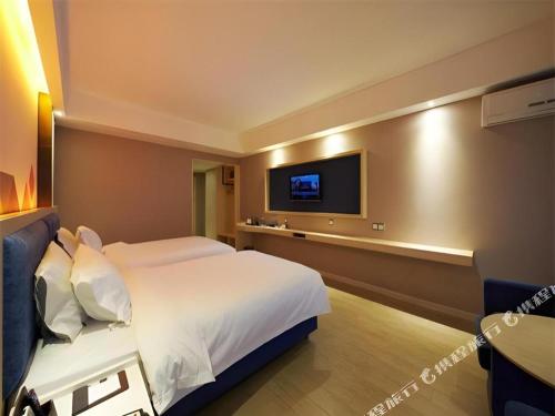 a hotel room with a bed and a flat screen tv at Borrman Hotel Liuzhou High-Speed Railway Station in Liuzhou