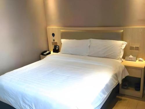 a bedroom with a large white bed and a desk at Borrman Hotel Liuzhou High-Speed Railway Station in Liuzhou