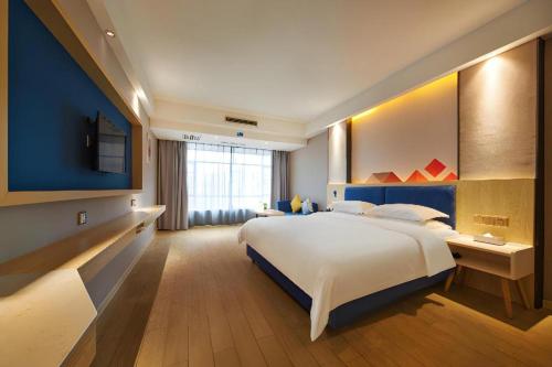 a bedroom with a large bed and a large window at Borrman Hotel Liuzhou High-Speed Railway Station in Liuzhou