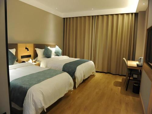 a hotel room with two beds and a television at Green Tree Inn Express Shandong Dezhou Qihe County Qiqifa in Sangzidian