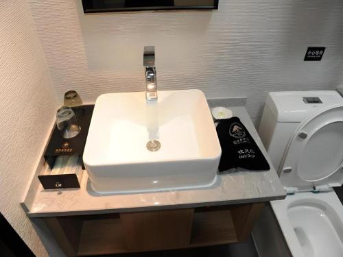 a bathroom with a sink and a toilet at Green Tree Inn Express Shandong Dezhou Qihe County Qiqifa in Sangzidian