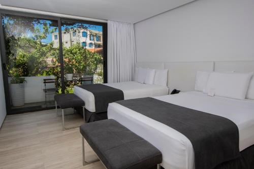 a hotel room with two beds and a large window at Golden Bay Galapagos in Puerto Baquerizo Moreno