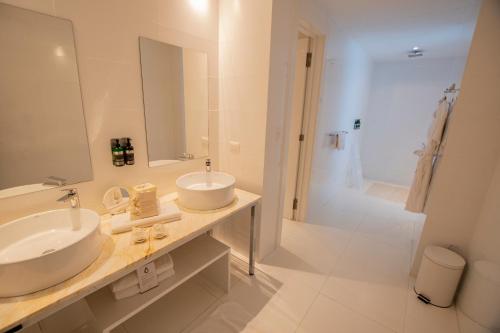 a white bathroom with two sinks and a shower at Golden Bay Galapagos in Puerto Baquerizo Moreno
