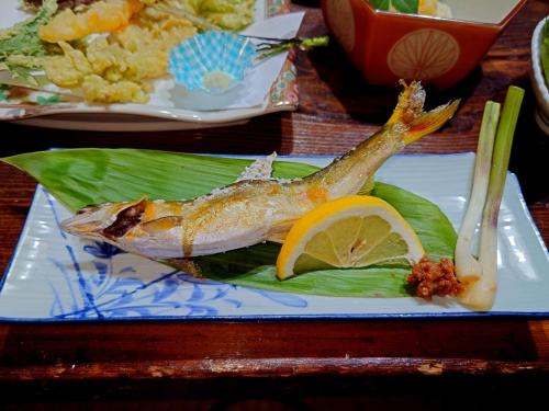 a fish on a plate with a lemon on a leaf at 咲花温泉 ホテル丸松 in Gosen