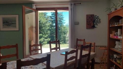 a dining room with a table and chairs and a window at Les balcons du Haut-Forez in Chalmazel Jeansagniere