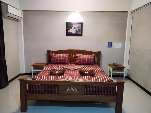 a bedroom with a bed with red and white sheets at Kidthuengpark in Si Racha