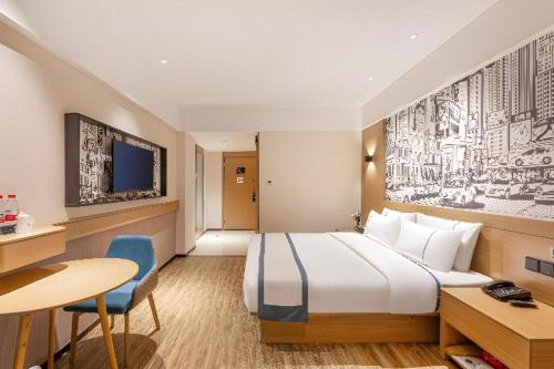 une chambre d'hôtel avec un grand lit et un bureau dans l'établissement City Comfort Inn Yancheng Xihuan Road Wanda Plaza, à Yancheng