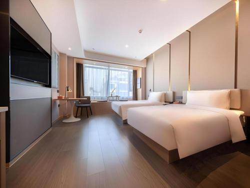 a hotel room with two beds and a flat screen tv at Atour Hotel Huainan Railway Station Commercial and Cultural Square in Huainan