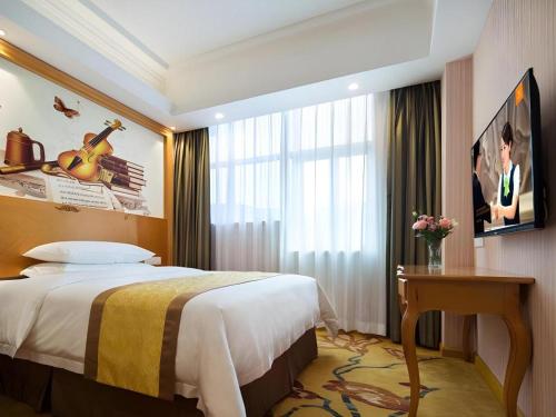 a hotel room with a bed and a table and a window at Vienna Hotel Guangdong Huidong Herung Pedestrian Street in Huidong