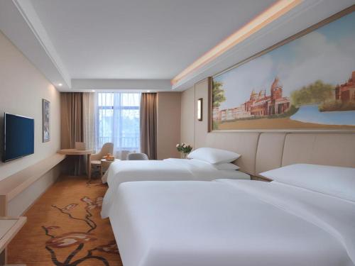 a hotel room with three beds and a painting on the wall at Vienna Hotel Zhejiang Tongxiang Puyuan in Jiaxing