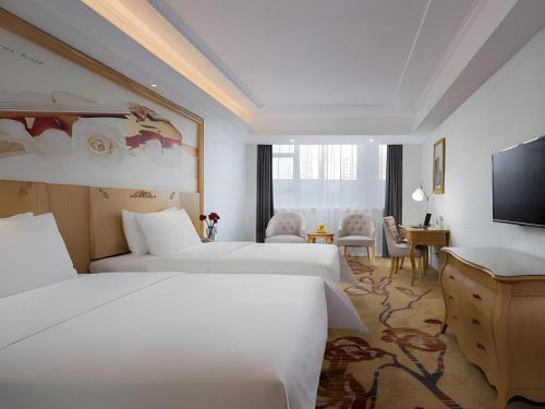 a hotel room with two beds and a flat screen tv at Vienna Hotel Guangdong Huizhou Huabianling Square in Huizhou