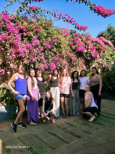 a group of women posing for a picture in front of flowers at Mistletoe Homestay & Cafe in Munnar