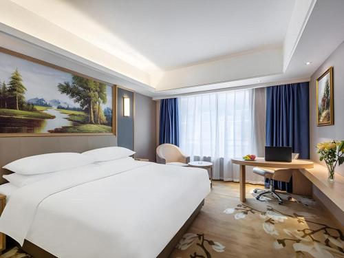 a bedroom with a large white bed and a desk at Vienna Hotel Guangdong Zhongshan South Area Passenger Station in Zhongshan