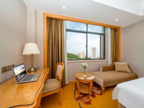 a hotel room with a desk with a laptop on it at Vienna Hotel Guangxi Fangcheng in Fangcheng