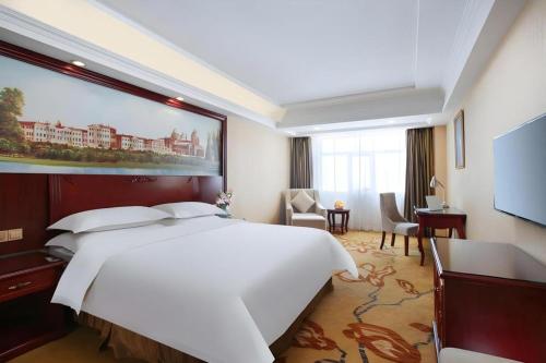 a hotel room with a large white bed and a desk at Vienna Hotel Anhui Fuyang Yingshang Yingbin Avenue in Fuyang