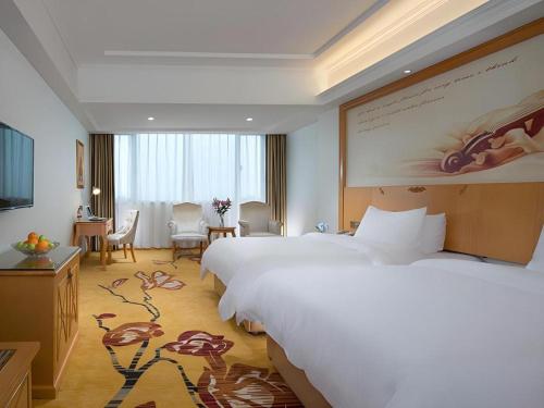 a hotel room with a large bed and a television at Vienna Hotel Guangdong Zhaoqing Sihui Center Jade Expo Market in Zhaoqing