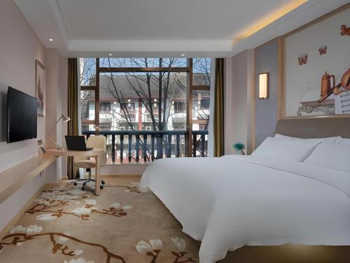 a bedroom with a bed and a desk and a window at Vienna Hotel Guizhou Liupanshui Shuicheng Ancient Town in Shuicheng