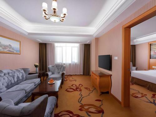 a living room with a couch and a bed and a television at Vienna Hotel Guangdong Shantou South Bus Station in Shantou