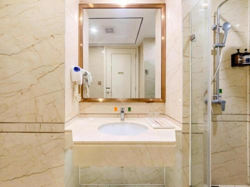 a bathroom with a sink and a mirror at Vienna Hotel Guangdong Shantou South Bus Station in Shantou