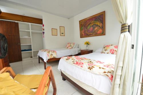 a bedroom with two beds and a chair at CASABLANCA, la calidez de tu hogar en Villeta in Villeta