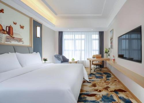 a hotel room with a large bed and a desk at Vienna Hotel Chengdu University of Pertroleum Metro Station in Chengdu