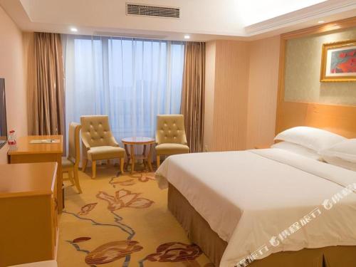 a hotel room with a bed and a table and chairs at Vienna Hotel Guangxi Guilin Xing'an in Guilin