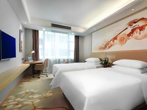 a hotel room with two beds and a desk at Vienna Hotel Guangxi Hechi Jinchengjiang Baima Street in Hechi