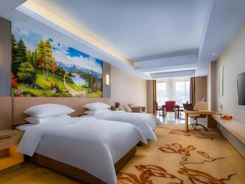 two beds in a room with a painting on the wall at Vienna Hotel Anhui Fuyang Funan Bailing Apartment in Funan