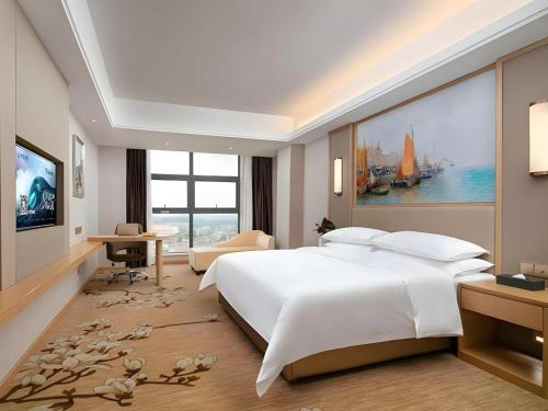 a bedroom with a large white bed and a tv at Vienna Hotel Jiangxi Fengcheng Fnegkuang in Fengcheng