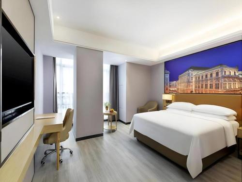 a bedroom with a bed and a desk and a tv at Vienna Hotel Jiangxi Shangrao High-Speed Railway Station in Shangrao