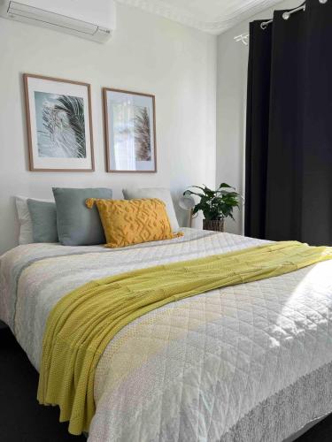 a bedroom with a bed with a yellow blanket on it at Mildura Park Views in Mildura