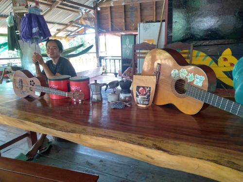 a woman sitting at a table with two acoustic guitars at Smiling Lao River View in Don Det