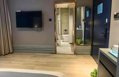 a room with a bathroom with a television on the wall at LANOU Hotel Henan Luoyang Wanda Plaza Wangfujing in Luoyang