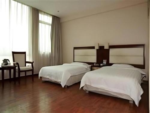 a bedroom with two beds and a desk and a chair at Yidun Hotel Foshan Luocun in Foshan