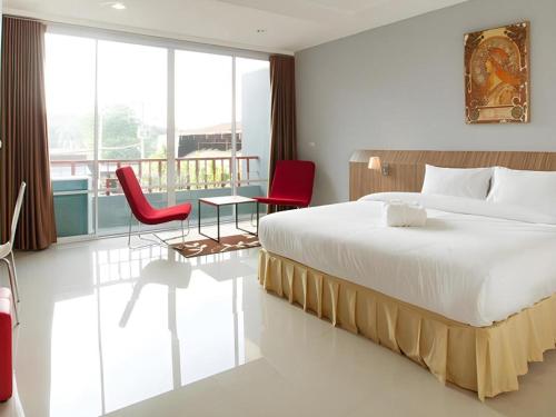 a bedroom with a bed and two red chairs at Soontree House Hotel in Udon Thani