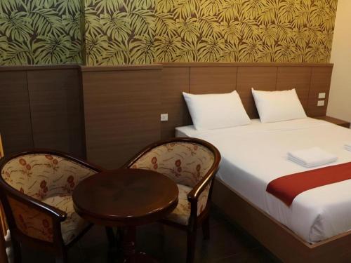 a room with a bed and two chairs and a table at The Grace Residence in Surin